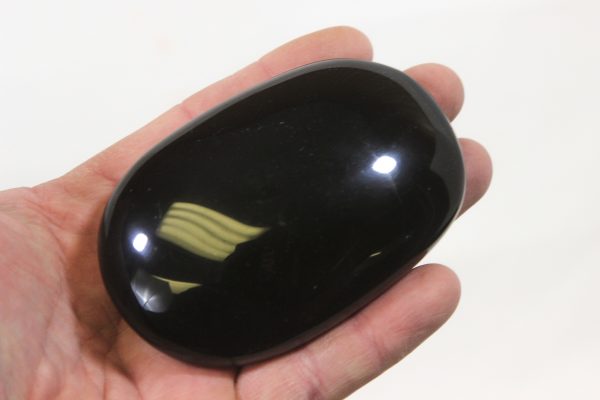 Black Obsidian massage stone in hand for size comparison