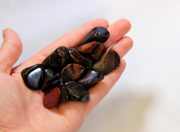 Several Black and Red Hematite Stones in hand for size comparison