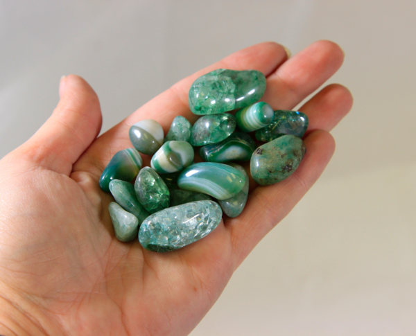 Several Green Glass Stones in hand for size comparison