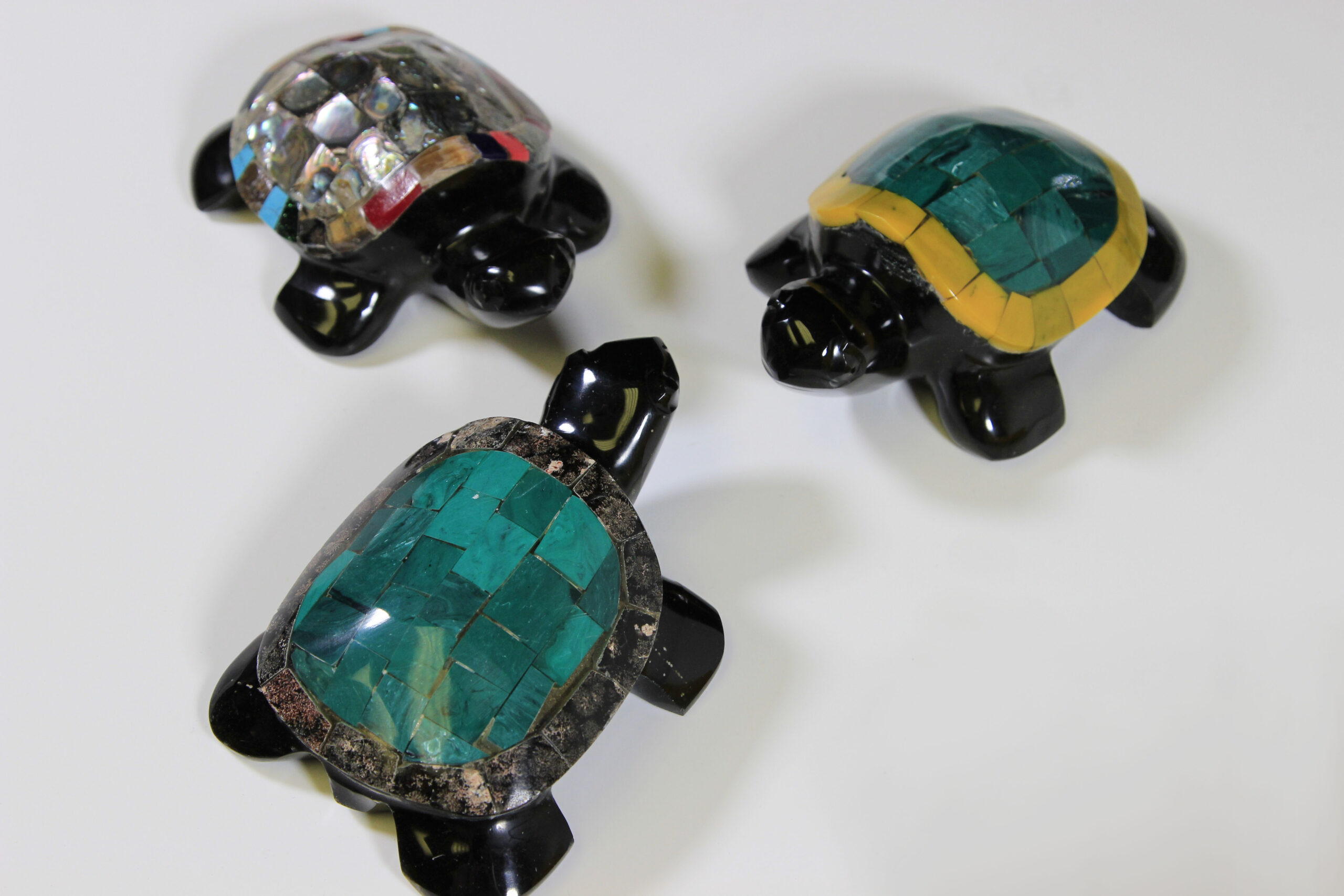 Three obsidian turtle figurines with assorted colored shells