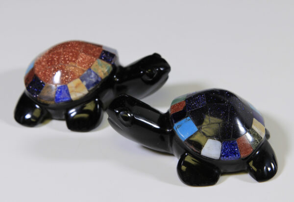 Two obsidian turtle figurines with assorted colored shells