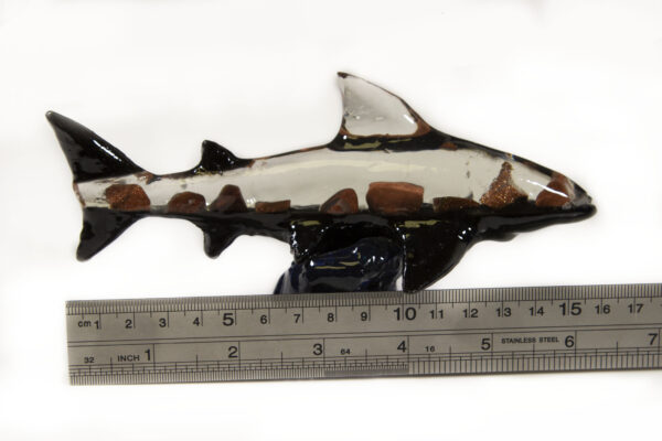 White and red mineral shark figurine next to ruler for size comparison