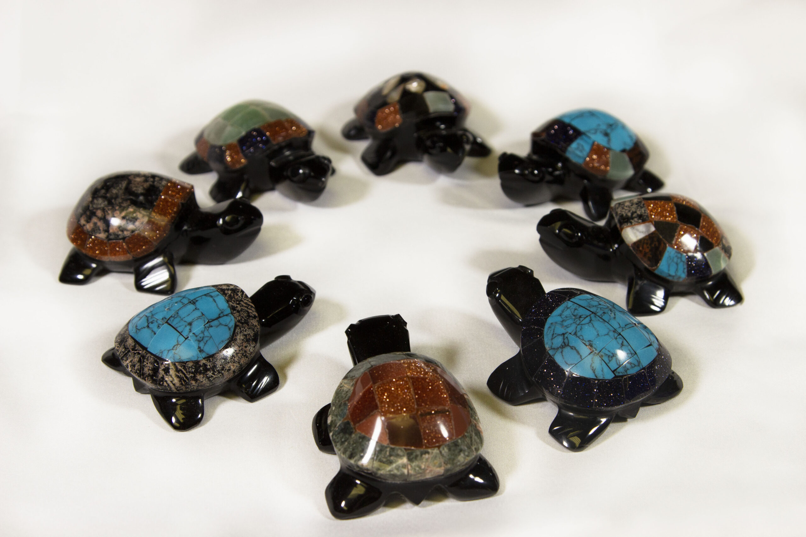 Eight small black decorative turtles with assorted colored shells