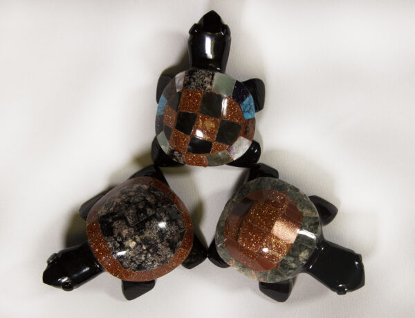 Three small black decorative turtles with assorted colored shells