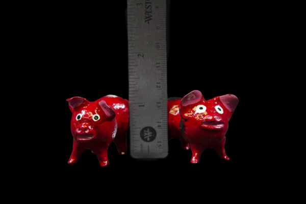 Red Looseneck Pig Figurines next to ruler for size comparison
