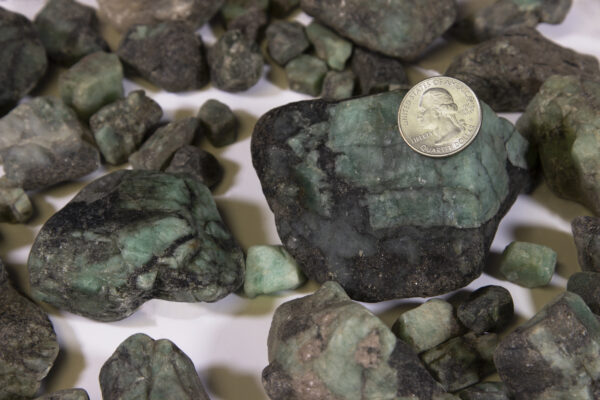 Pile of Large Emerald Stones with coin for size