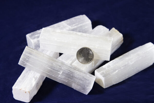 Pile of four to five inch Selenite Rough Wands with quarter for size