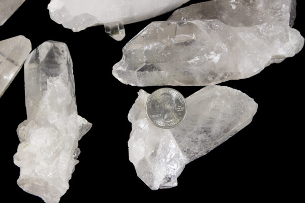 quartz points in a pile with quarter to show size