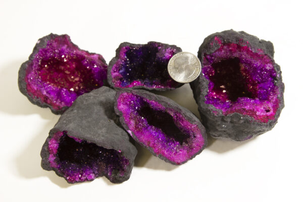 assorted pink/purple dyed geodes with quarter to show scale