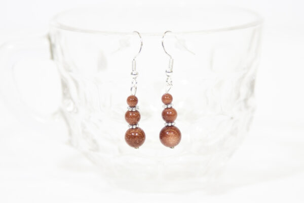 Goldstone Earrings hanging on a glass cup