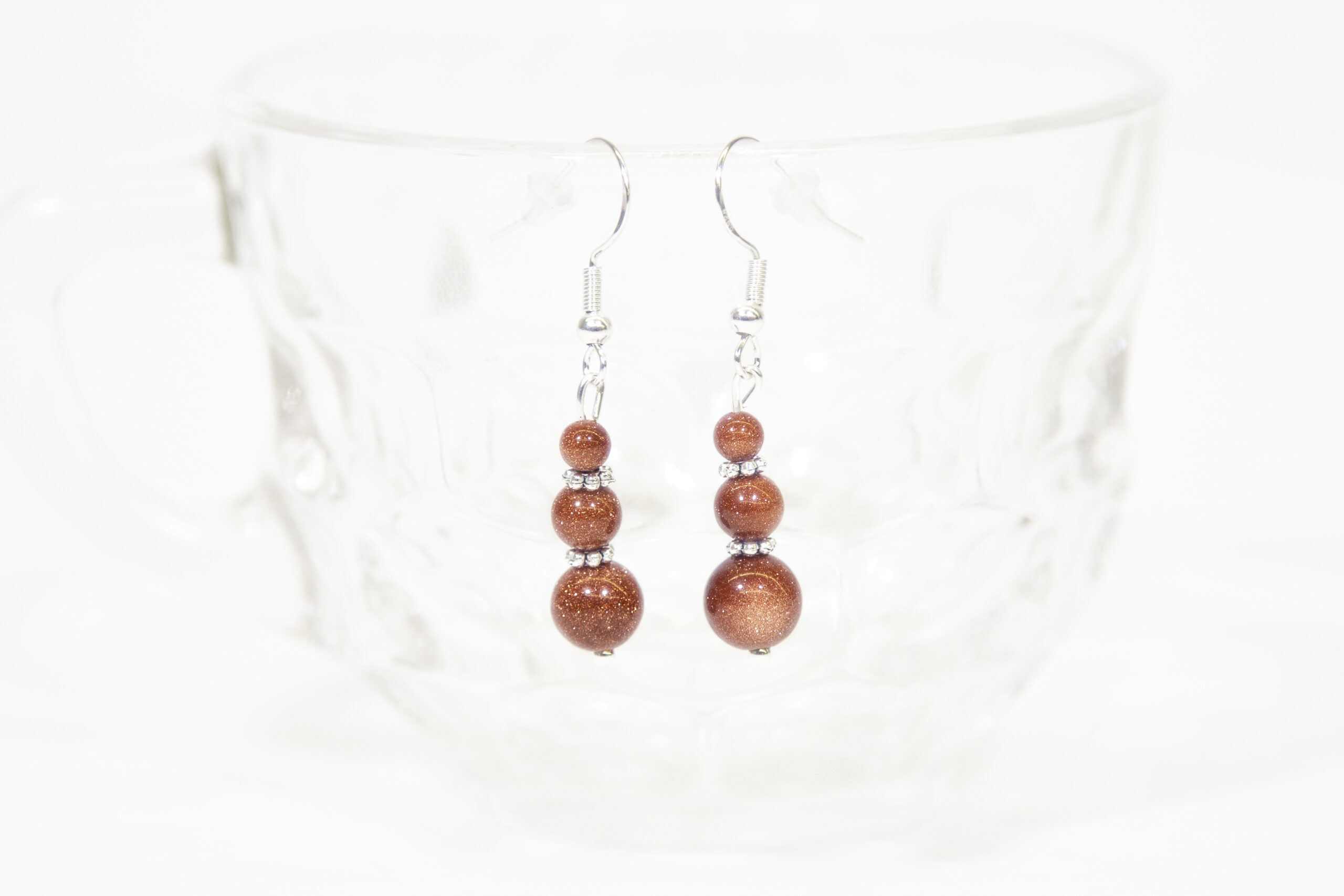 Goldstone Earrings hanging on a glass cup