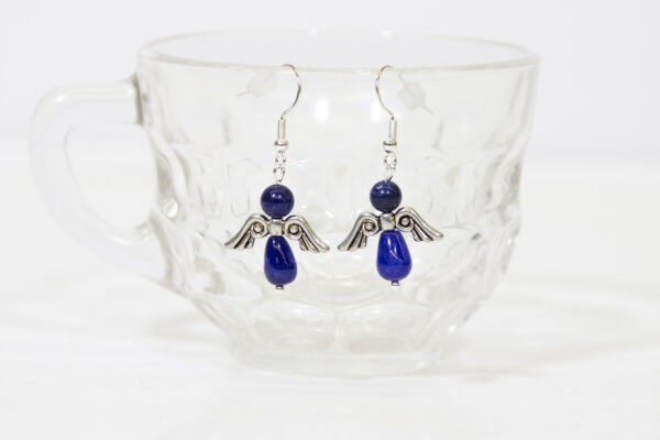 Blue Lapis Angel Earrings hanging on a cup